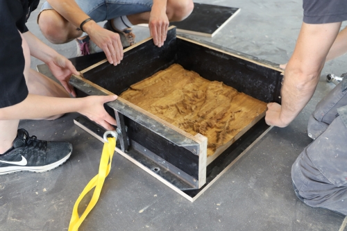 Installation du coffrage autour du fond de moule en bois pour créer un relief sur les blocs de terre crue ©amàco
