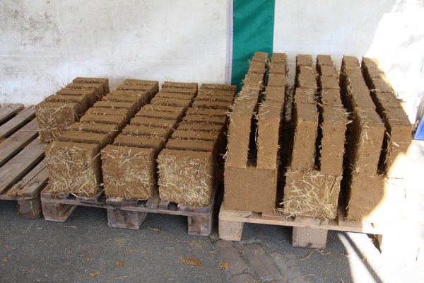 Briques de terre crue séchées stockées sur palette en attendant d'être mises en œuvre dans les cloisons de l'extension de l'école